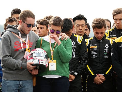 The mother and brother of Anthoine Hubert hold the helmet of F2 driver Anthoine Hubert during a moment of silence at the Belgian GP last year.