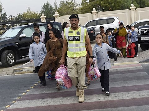 Sharjah police officers helping students and parents cross the road on the first day of school after summer vacation on Sunday.