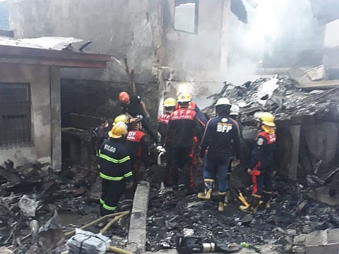 Filipino firefighters search for victims' bodies after a medical evacuation aircraft crash on a residential area in Barangay Pansol, Laguna., damaging two adjacent resorts.