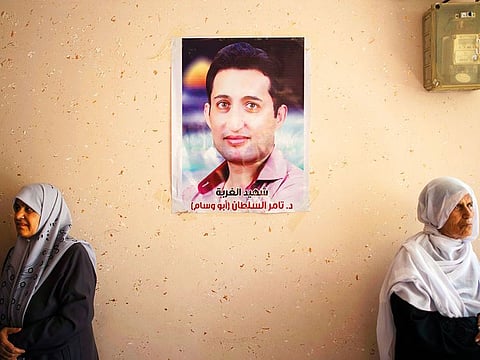 Relatives of Palestinian activist Tamer Sultan, 38, mourn next to a picture of him on a wall in his family home during his funeral in the town of Beit Lahiya, northern Gaza Strip.