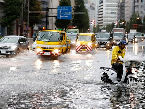 A man rides a moped through a flooded street due to a typhoon in Tokyo