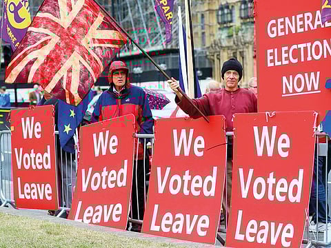 A pro-Brexit protester waves a Union flag as he stands with “We Voted Leave” placards outside the Houses of Parliament in London.