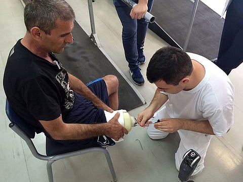 A man adjusts a prosthesis on a volunteer on September 9, 2019 in Zurich. A new device allows users to feel prosthetic legs, improving mobility.