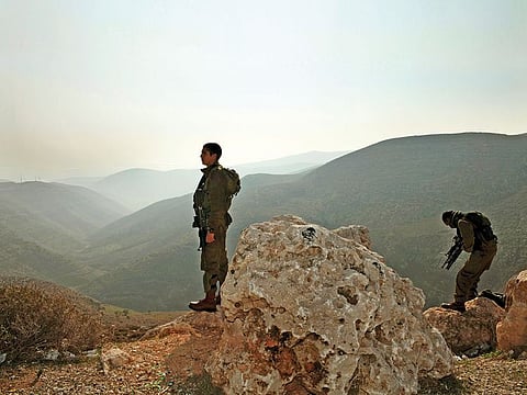 Israeli occupation soldiers stand guard as members of parliament tour the Jordan Valley near Bardala, West Bank.