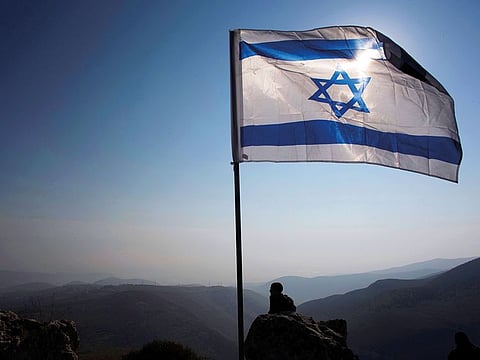 An Israeli occupation soldier stands guard under an Israeli national flag during a tour made by Israeli parliament members in the Jordan Valley near the Jewish colony of Maale Efrayim January 2, 2014.