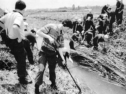 In this July, 1993, photo, South Korean investigators examine the scene following a killing in Hwaseong, South Korea.