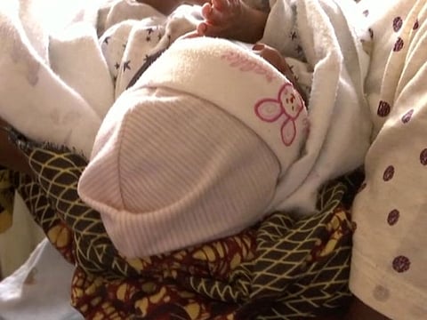 A still image taken from a video shows a woman, who was freed by police with other girls and women that were held captive, carrying a baby as she waits at a police station in Lagos