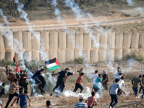 Palestinian protesters run for cover from tear gas fired by Israeli forces during clashes with following a demonstration along the border with Israel east of Bureij in the central Gaza Strip on September 20, 2019