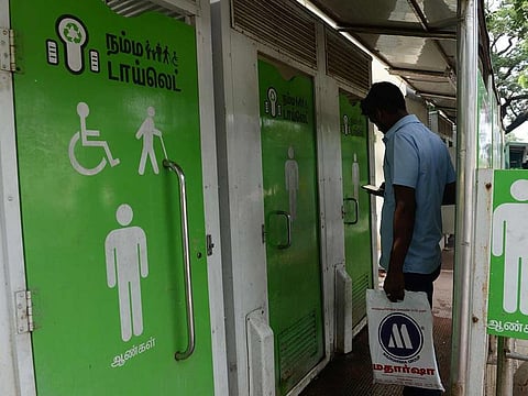 In this file photo taken on November 15, 2017 an Indian resident checks his phone as he waits to use a public toilet on a street in Chennai. India is to be declared "open-defecation free" by Prime Minister Narendra Modi on October 2, although experts question his bold claim that all 1.3 billion people in the country have access to a toilet.