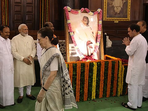 Indian Prime Minister Narendra Modi, second left, watches Congress party leader Rahul Gandhi, right, pay tribute in front of a portrait of Mahatma Gandhi, as Congress President Sonia Gandhi walks past, on the 150 birth anniversary of Mahatma Gandhi, at the Parliament House in New Delhi, India.