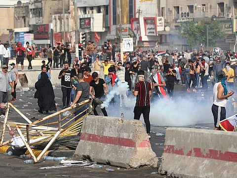 Protesters react after Iraqi security forces fired tear gas during a protest in Tahrir Square, in central Baghdad, Iraq, Tuesday, Oct. 1, 2019.