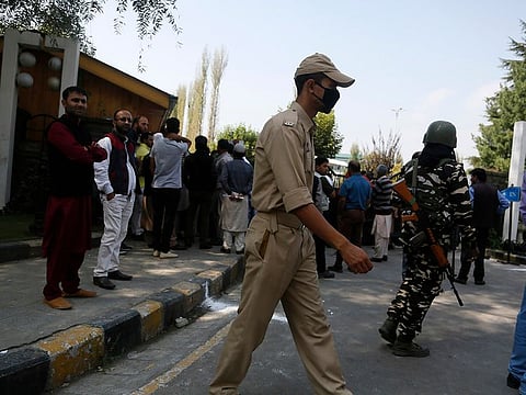 Indian policeman and a paramilitary soldier guard as relatives of Kashmiri political workers who have been detained wait to meet them outside a hotel turned into a detention center in Srinagar, Indian controlled Kashmir, Wednesday, Oct. 2, 2019.