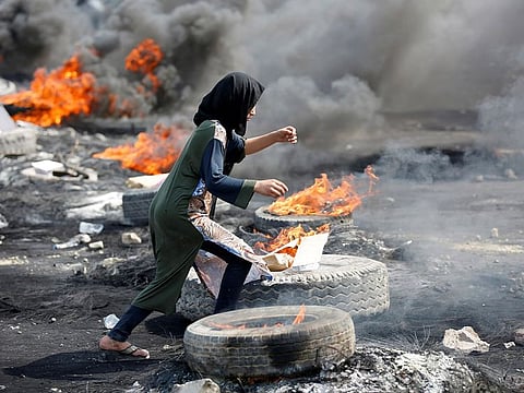 A demonstrator runs between burning tires during a curfew, two days after the nationwide anti-government protests turned violent, in Baghdad, Iraq October 3, 2019.