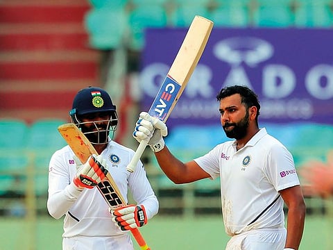 India's Rohit Sharma raises his bat after scoring a century during the fourth day of the first cricket test match against South Africa in Visakhapatnam, India.