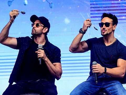 Bollywood actors Hrithik Roshan (L) and Tiger Shroff (R) pose for photographs during the promotion of their action thriller Hindi film 'War' in Mumbai on October 4, 2019. / AFP / Sujit Jaiswal