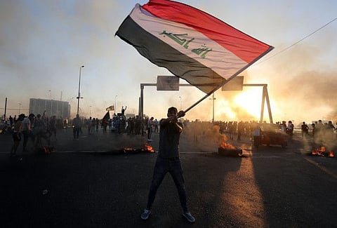 An Iraqi protester waves the national flag during a demonstration against state corruption, failing public services, and unemployment, in the Iraqi capital Baghdad on October 5, 2019.