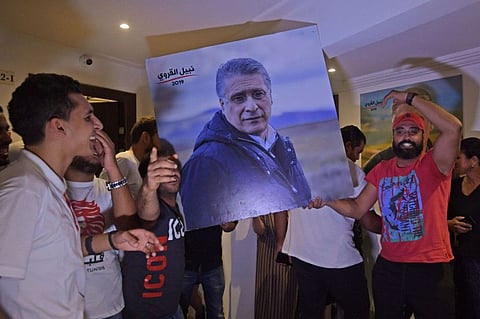 Supporters of Qalb Tounes (Heart of Tunisia) party of jailed business tycoon Nabil Karoui (portrait) cheer in reaction to the first exit polls at the party's office in Tunis on October 6, 2019.