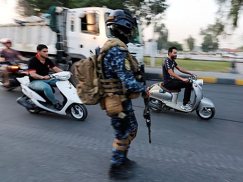 Men ride motorbikes past a member of Iraqi federal police in a street in Baghdad, Iraq October 7, 2019.