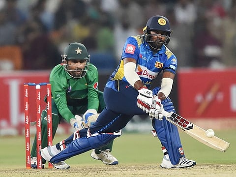 Sri Lanka's Bhanuka Rajapaksa (R) plays a shot as Pakistan's captain and wicketkeeper Sarfraz Ahmed looks on during the second Twenty20 International cricket match at the Gaddafi Cricket Stadium in Lahore on October 7, 2019.