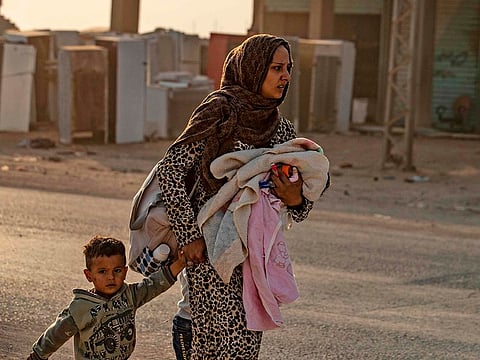 A woman flees with her children amid Turkish bombardment on Syria's northeastern town of Ras Al Ain in the Hasakeh province along the Turkish border on October 9, 2019.