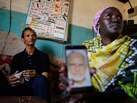Gerald Erebon sits with his aunt, Scolastica Apayo, as she holds a phone displaying a photo of the Rev. Mario Lacchin, during an interview at her home in the Isiolo area of the Archers Post settlement in Kenya.