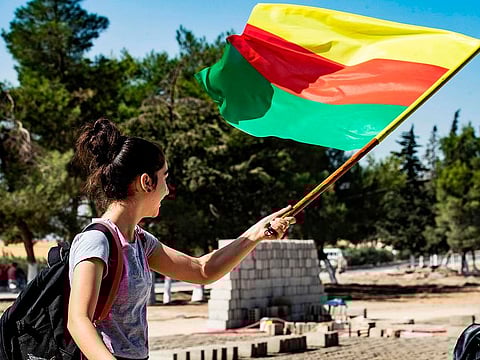 A young girl waves the flag of Kurdistan during a demonstration by Syrian Kurds against Turkish threats to launch a military operation on their region