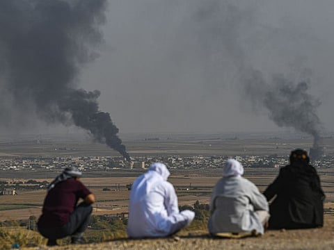 People look on as smoke rises from the Syrian town of Ras Al Ain, in a picture taken from the Turkish side of the border in Ceylanpinar on October 11.