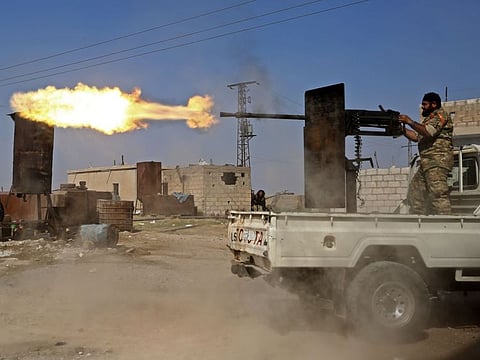 A Turkish-backed Syrian fighter fires during clashes in the border town of Ras Al Ain on October 13, 2019, as Turkey and its allies continue their assault on Kurdish-held border towns in northeastern Syria.