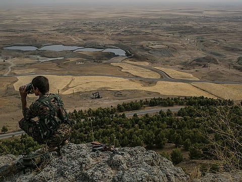 A Syrian Kurdish fighter patrols on a hill overlooking a huge oil field near the village of Derik, Syria, July 30, 2015. The violence precipitated by the American withdrawal from Syria is an outcome of tensions that have been building since the conflict began more than eight years ago.