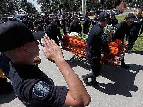 Michoacan state police salute as others push the casket of a slain colleague at the end of a memorial service at the public security department headquarters for Michoacan, in Morelia, Mexico, Tuesday, Oct. 15, 2019.
