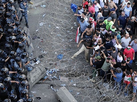 Riot police stand guard as anti-government protesters try to remove a barbed-wire barrier to advance towards the government buildings during a protest in Beirut, Lebanon, Saturday, Oct. 19, 2019.