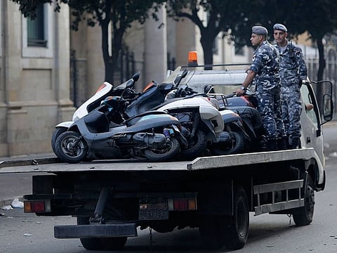 Policemen collect scooters left by anti-government protesters after the aftermath of violent protests against the Lebanese government in Beirut, Lebanon, Saturday, Oct. 19, 2019