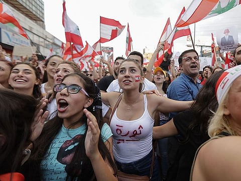 Lebanese demonstrators wave national flags on a highway linking Beirut to north Lebanon, in Zouk Mosbeh on October 19, 2019, a day after demonstrations swept through the eastern Mediterranean country in protest against dire economic conditions.