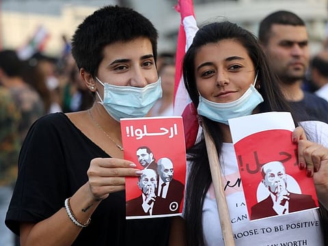 Women wave signs reading in Arabic "leave" and showing the faces of Lebanon's President Michel Aoun, Prime Minister Saad Hariri, and Parliament Speaker Nabih Berri, during a protest outside the presidential palace in Baabda, east of the capital Beirut, on October 18, 2019 against dire economic conditions.