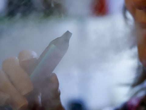 FILE - In this Friday, Oct. 4, 2019 file photo, a woman uses her vaping device in Harmony, Pa. Health officials say a teenager in Montana has died of a lung disease associated with a national outbreak of vaping-related illnesses. The Montana Department of Public Health and Human Services said Tuesday, Oct. 15, 2019, it was the state's first recorded death connected to e-cigarette use. (AP Photo/Keith Srakocic, File)