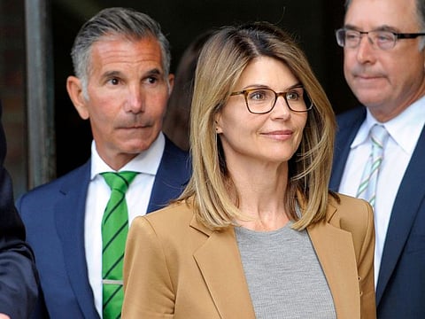 (FILES) In this file photo taken on April 03, 2019, ctress Lori Loughlin, with husband Mossimo Giannulli (L), exits the courthouse after facing charges for allegedly conspiring to commit mail fraud and other charges in the college admissions scandal at the John Joseph Moakley United States Courthouse in Boston. Loughlin was slapped with an additional charge related to America's wide-ranging college admissions scandal on October 22, 2019, increasing the likelihood that she could serve time in prison. The star of 1980s-90s sitcom "Full House," her husband and nine other parents now face the charge of conspiracy to commit federal programs bribery on top of previous charges, prosecutors said. / AFP / Joseph Prezioso