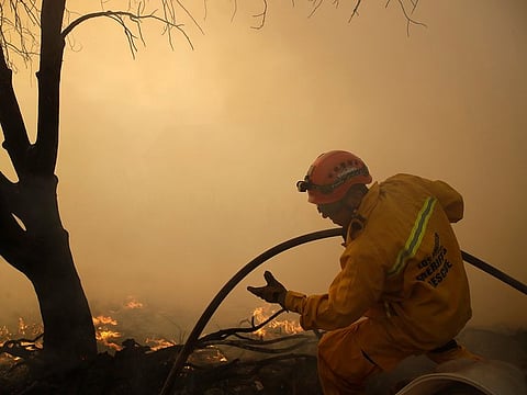 A member of the Los Angeles Sheriff's Dept. walks on top of a ridge as a wildfire approaches the backyard of a home Thursday, Oct. 24, 2019, in Santa Clarita, Calif.