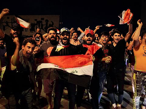 People wave the Iraqi national flags as they take part in an anti-government demonstration at the Tahrir Square in Baghdad, on October 24, 2019 to protest against the country's political system.
