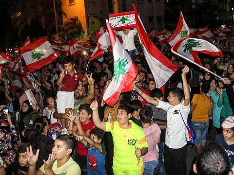 Youths wave Lebanese national flags as they gather during a demonstration on the eighth day of protest against tax increases and official corruption in the southern city of Sidon on October 24, 2019. / AFP / Mahmoud ZAYYAT