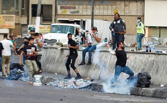 A demonstrator throws a tear gas bomb during a protest over corruption, lack of jobs, and poor services, in Baghdad, Iraq October 27, 2019.