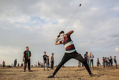 A Palestinian protester uses a slingshot to hurl stones during clashes with Israeli forces following a demonstration along the border with Israel east of Khan Yunis in the southern Gaza strip on October 25, 2019