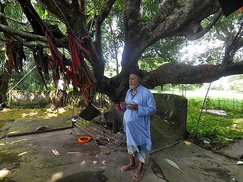 Haji Matibar Rahman prays by a Shivling (statue of Hindu deity Shiva), after offering flowers at the Hindu religious icon symbolic of Lord Shiva.