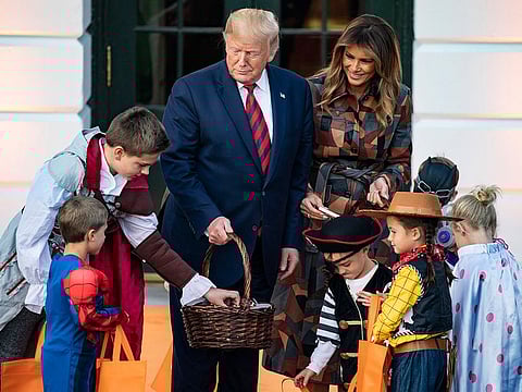 President Donald Trump and first lady Melania Trump hand out candy to costumed children for Halloween on the South Lawn of the White House in Washington