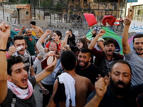 Anti-government protesters celebrate after Lebanon Prime Minister Saad Hariri announced he is submitting his resignation, meeting one of their main demands, in front of the government palace in Beirut, Lebanon, Tuesday, Oct. 29, 2019.