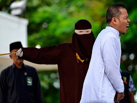 Aceh Ulema Council member Mukhlis reacts as he is whipped in public by a member of the Sharia police in Banda Aceh on October 31, 2019.