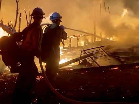 Firefighters direct water on a burning house during wildfires in San Bernardino, California, US, October 31, 2019