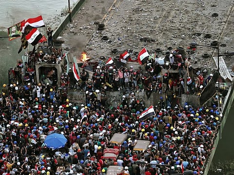 Anti-government protesters control some barriers set by Iraqi security forces to close the bridge leading to the Green Zone during ongoing protests in Baghdad.
