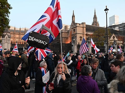 Brexiteers wave Union flags as they demonstrates outside the Houses of Parliament in Westminster, central London on October 31, 2019