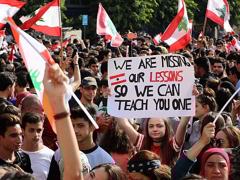 Lebanese students from various schools wave national flags and shout slogans as they gather in front of the Ministry of Education during ongoing anti-government protests, in the capital Beirut on November 7, 2019.