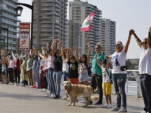 FILE - In this Sunday, Oct. 27, 2019 file photo, anti-government protesters form a human chain as a symbol of unity, during ongoing protests against the Lebanese government, on the Mediterranean waterfront promenade, in Beirut, Lebanon. Protestors’ demands pit them against leaders they accuse of stoking fear to secure sectarian allegiance and of trading economic favors for loyalty. They also put them up against regional allies of local factions. The power-sharing system has largely contained sectarian animosities since the war ended but has also meant that jobs are often allotted according to sectarian quotas instead of merit. AP Photo/Bilal Hussein, File)